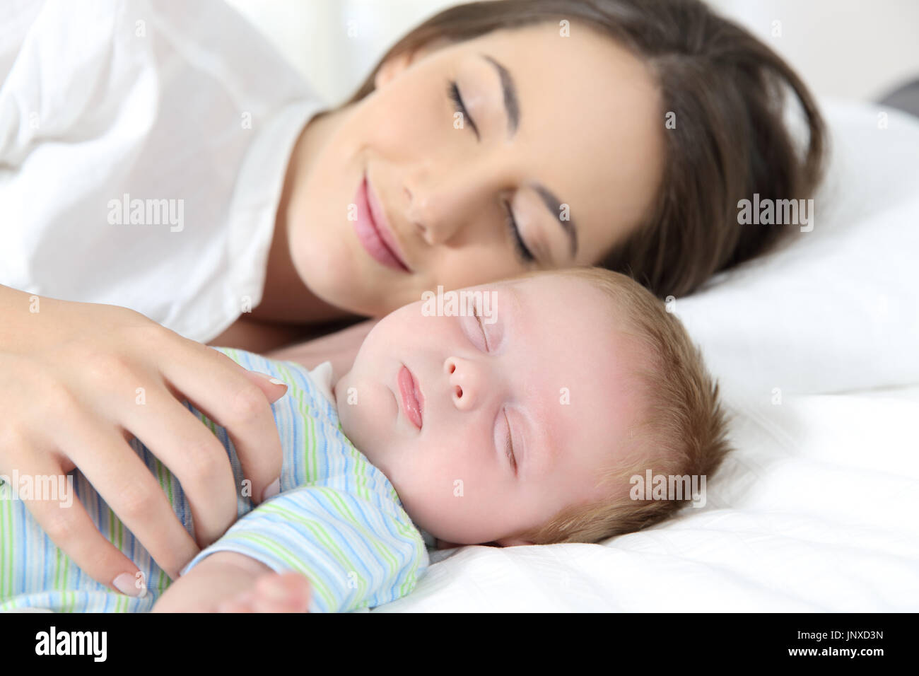 Portrait of a happy mother and baby sleeping together on bed Stock Photo