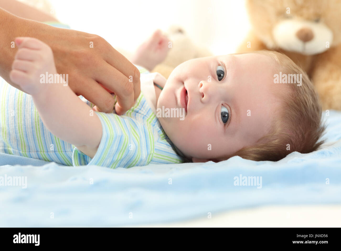 Portrait of a happy baby looking at you and a mother hand touching him Stock Photo