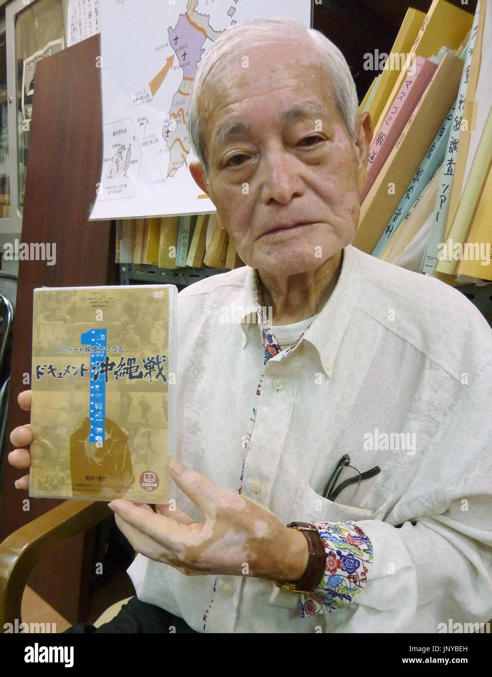 NAHA, Japan - Hiroaki Fukuchi, 81, leader of the Okinawa Historical Film Society, holds a 57-minute documentary on the 1945 Battle of Okinawa, in Naha, Okinawa Prefecture, in June 19, 2012. The civic group based in Naha recently reissued its documentary, originally released in 1995 as a video, in DVD format ahead of the 67th anniversary June 23 marking the end of the battle. (Kyodo) Stock Photo