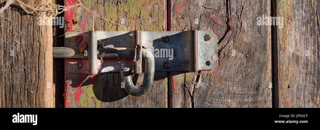 A banner panoramic image of an old slide bolt or pad bolt on a rustic stable door on the historic property Rowlee in Orange, NSW, Australia Stock Photo