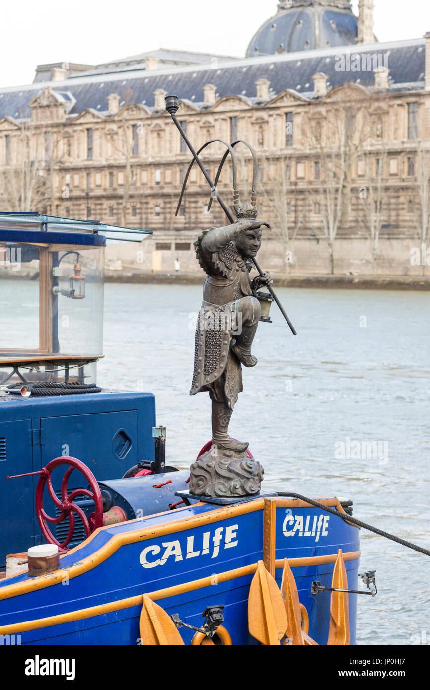 Paris, France - March 2, 2016: Figurehead on blue boat on the Seine, Louvre in the background across the river. Stock Photo