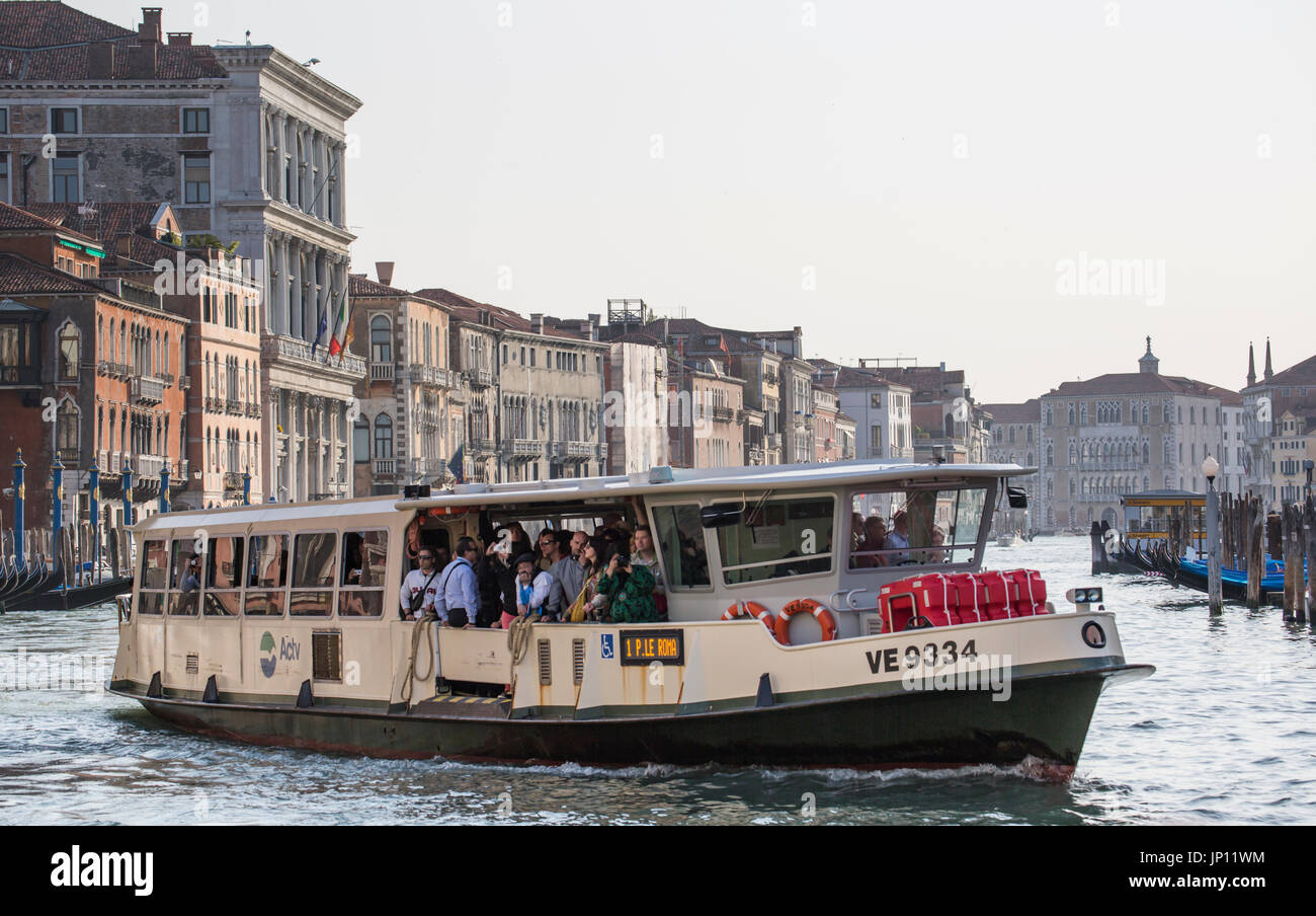 Venice, Italy - April 26, 2012: A vaporetto (water bus) full of passengers on the Grand Canal. The vaporettos are the main form of bulk transport in Venice, going up and down the Grand Canal making frequent stops and also across the lagoon. Stock Photo