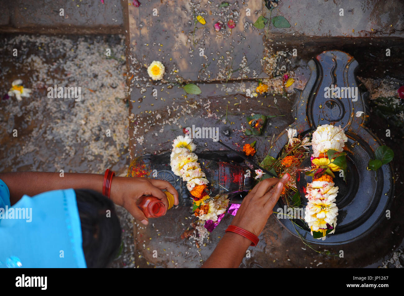 A woman's hands add finishing touches to a decorated Shiva lingam on Shivaratri Stock Photo