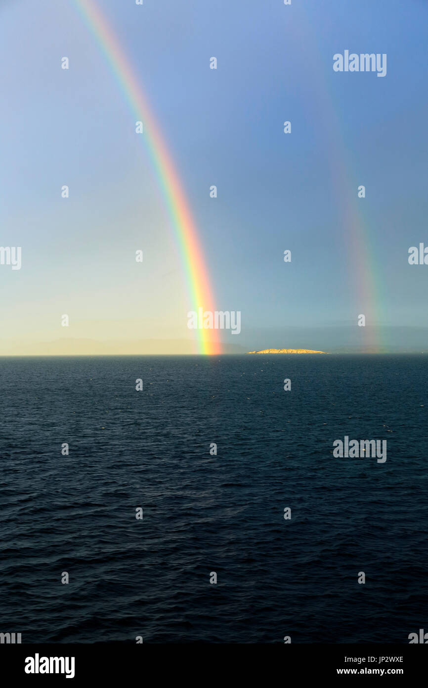 Seascape view of spectrum colours in rainbow over sea and island, Norway Stock Photo