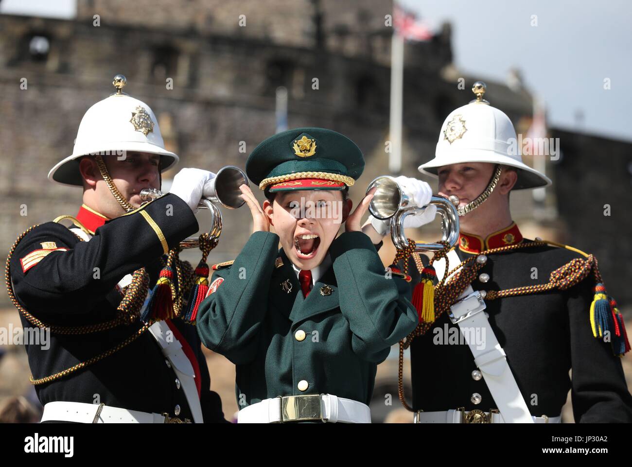 Buglers Sergeant Nathan Crossley(l) and Jason Morris from the Massed Bands of Her Majesty's Royal Marines with Sergeant Ayami Nakama from Japan's Ground Self Defence Force Central Band during a photocall on the Edinburgh Castle esplanade after the Royal Edinburgh Military Tattoo programme was revealed by Brigadier David Allfrey, chief executive and producer of the Tattoo. Stock Photo