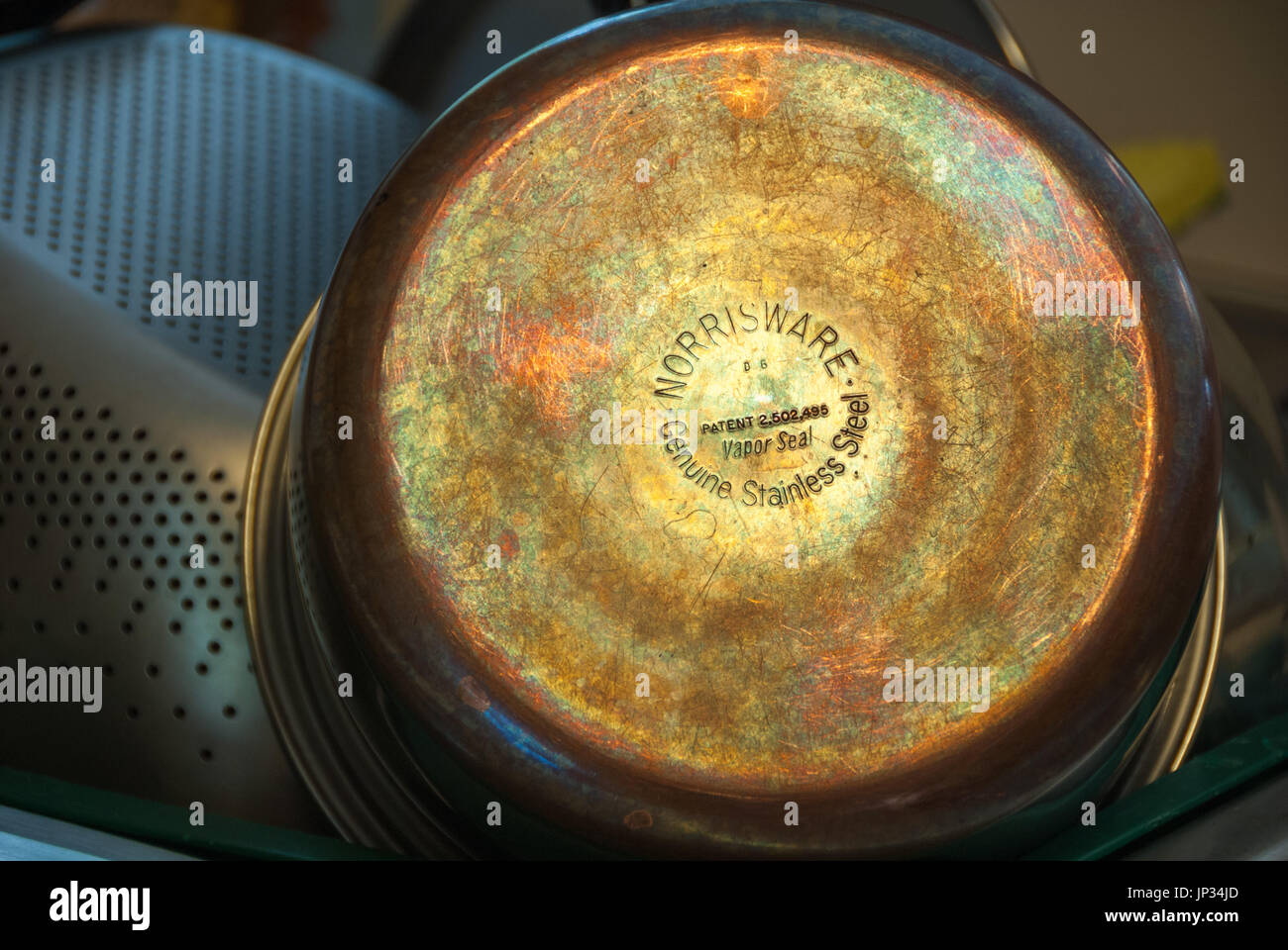 Reflecting light reveals the beautifully colored patina of copper bottom cookware. Stock Photo