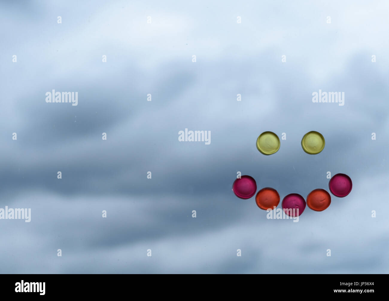 Smiley face made of sweet candy contrasting with clouded moody background Stock Photo