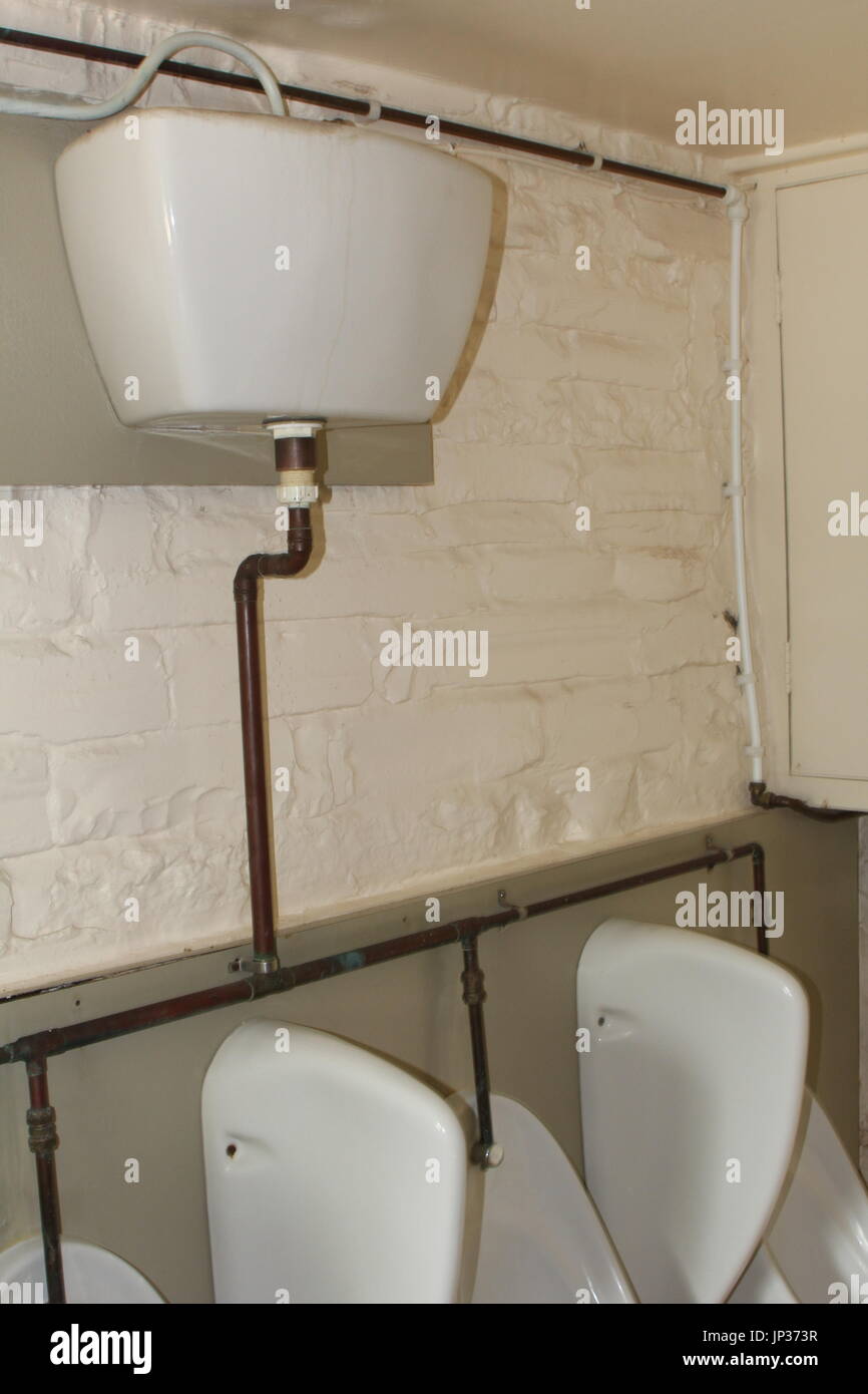 Old fashioned high level cistern feeding into urinals in a run down