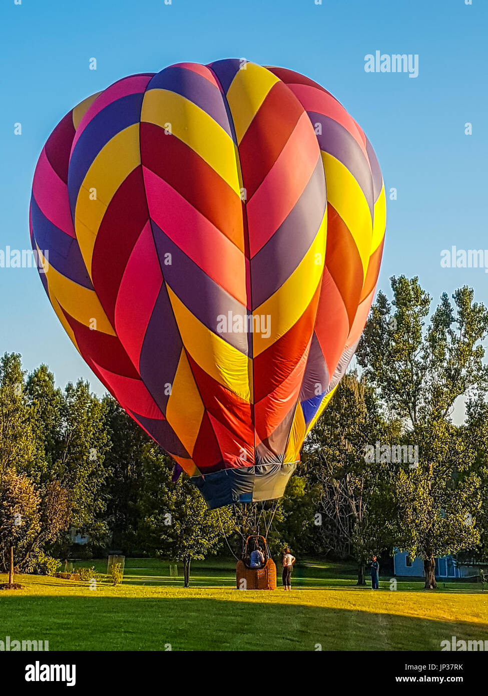 Hot air balloon landing on the lawn in a residential area: houses in the background; Missouri, Midwest Stock Photo