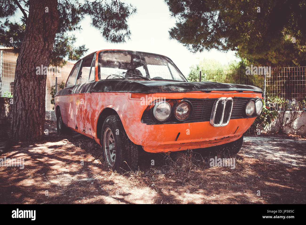 Old abandoned vintage car rusting under the tree. Vintage filter Stock Photo