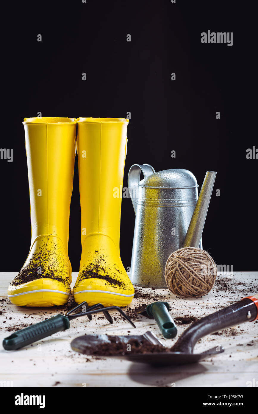 Close-up view of yellow rubber boots and garden boots isolated on black Stock Photo