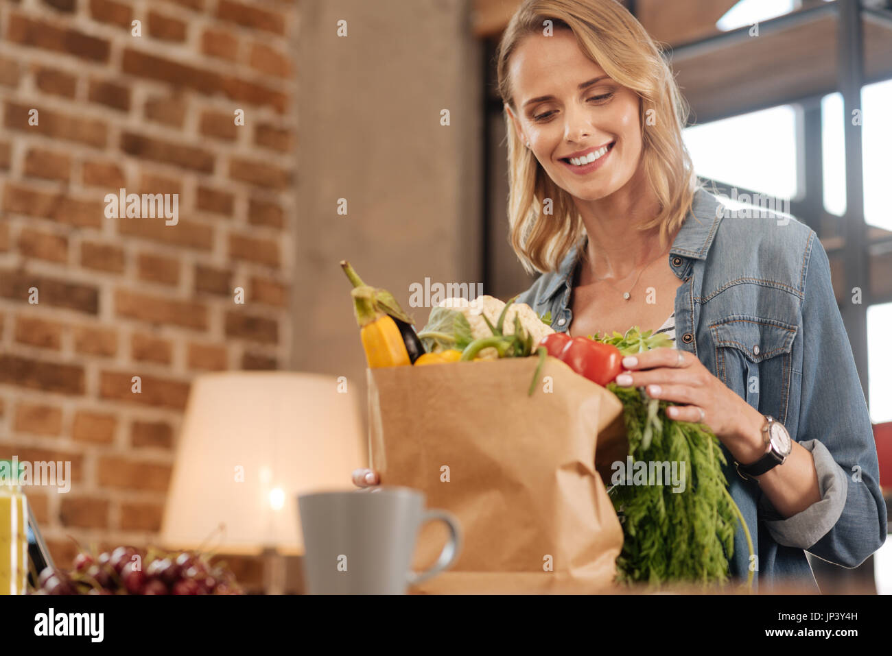 Admirable happy lady unpacking the paper bag Stock Photo