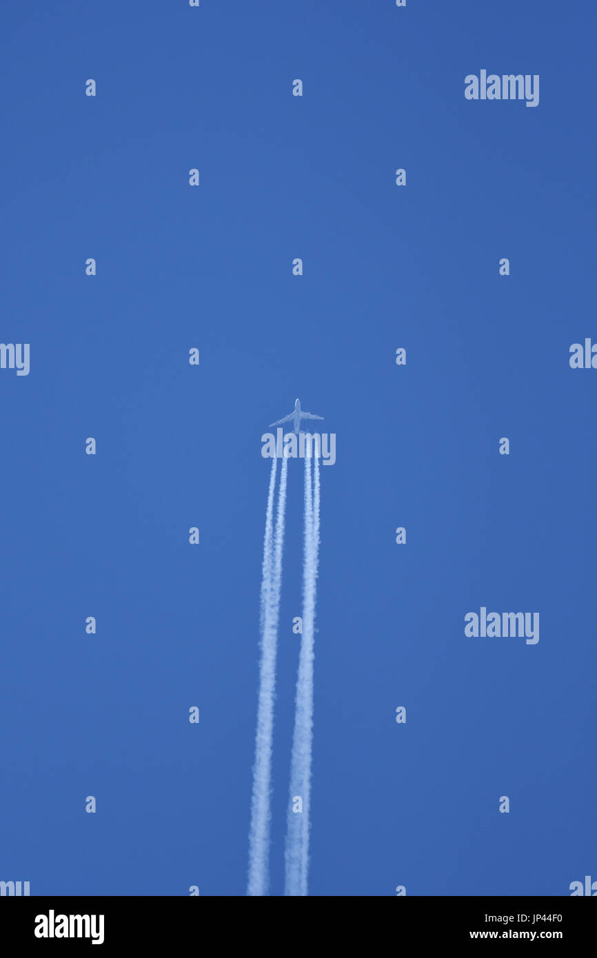 Jet aircraft in flight leaving vapour trails against a blue sky Stock Photo