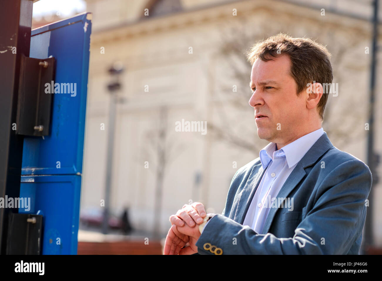 A middle age businessman checking the time on his watch and the ...