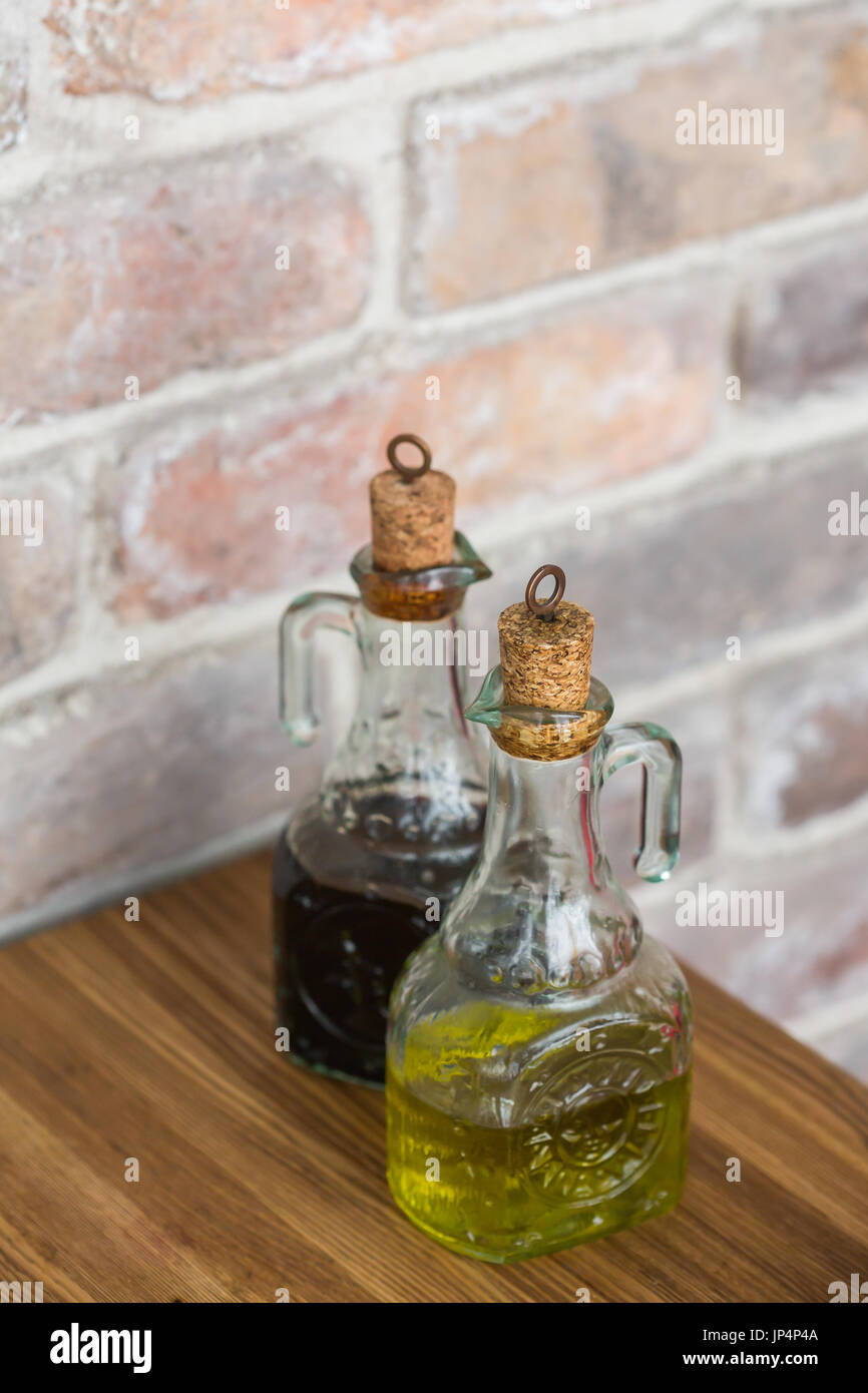 Oil and balsamic vinegar glass bottles with spouts on rustic brick wall