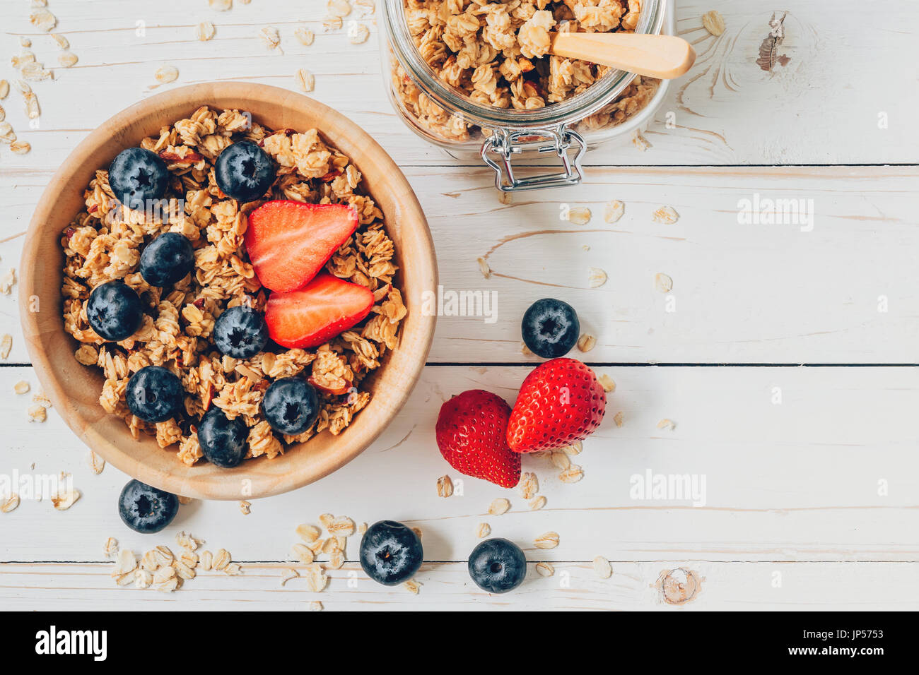 Homemade granola and fresh berries on wood table with space. Stock Photo