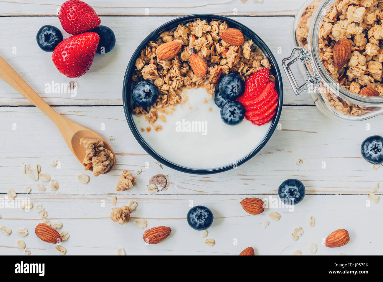 bowl of granola with yogurt, fresh berries, blueberries and nut on wood table. Stock Photo