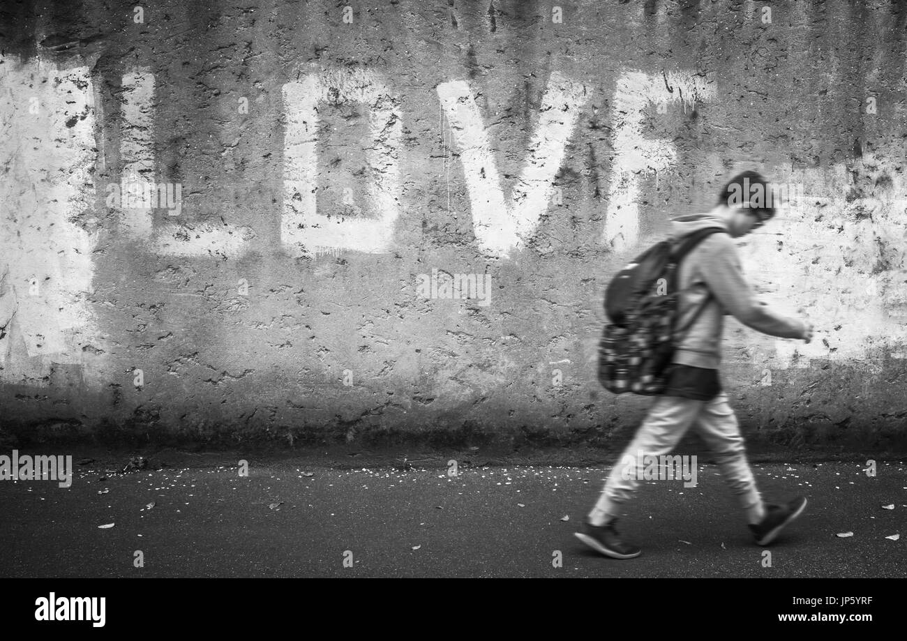 Schoolboy walking down the street with head bowed; love on background. Back to school. Stock Photo