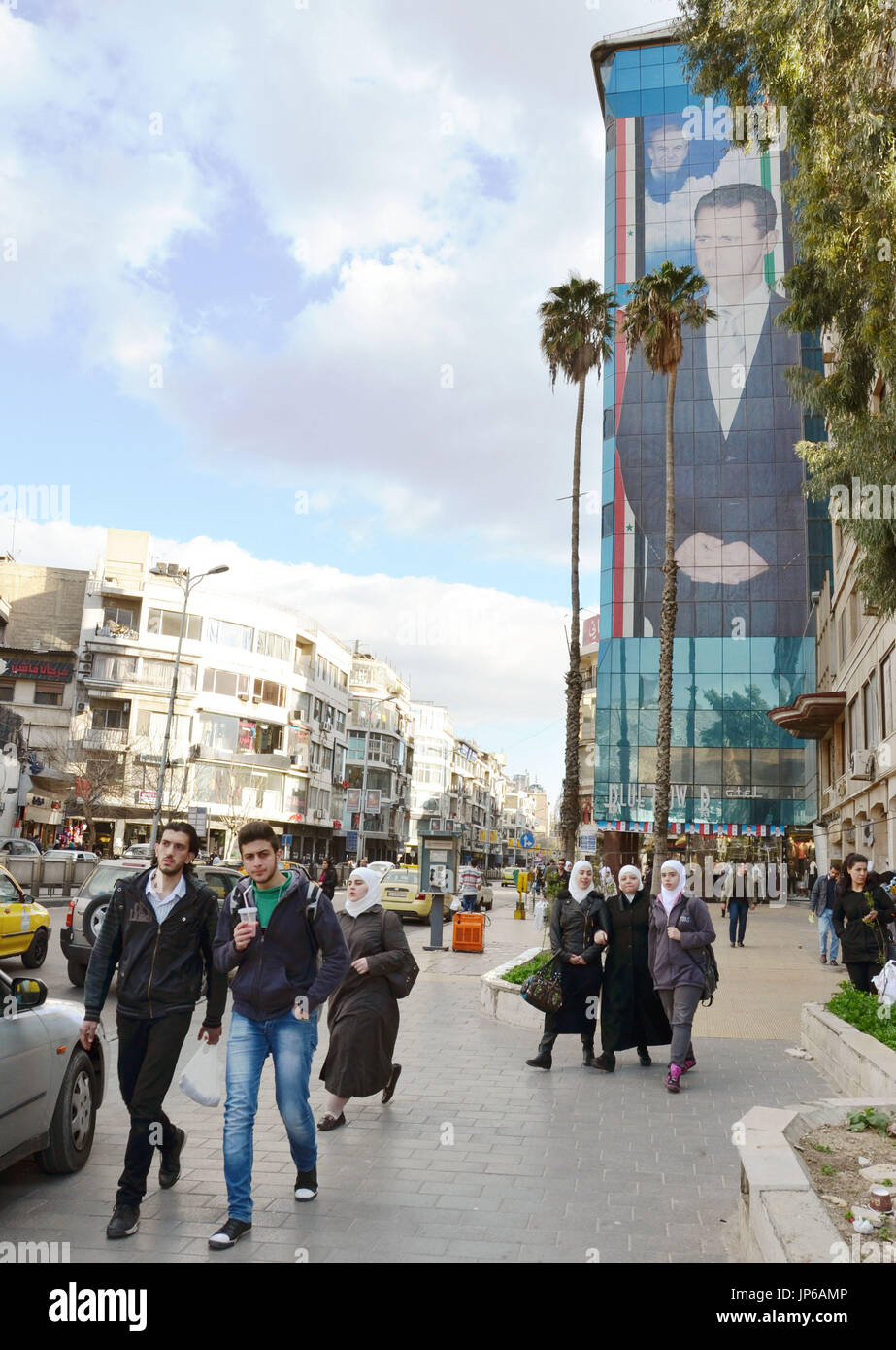 Citizens walk under a huge portrait of Syrian President Bashar Assad in ...