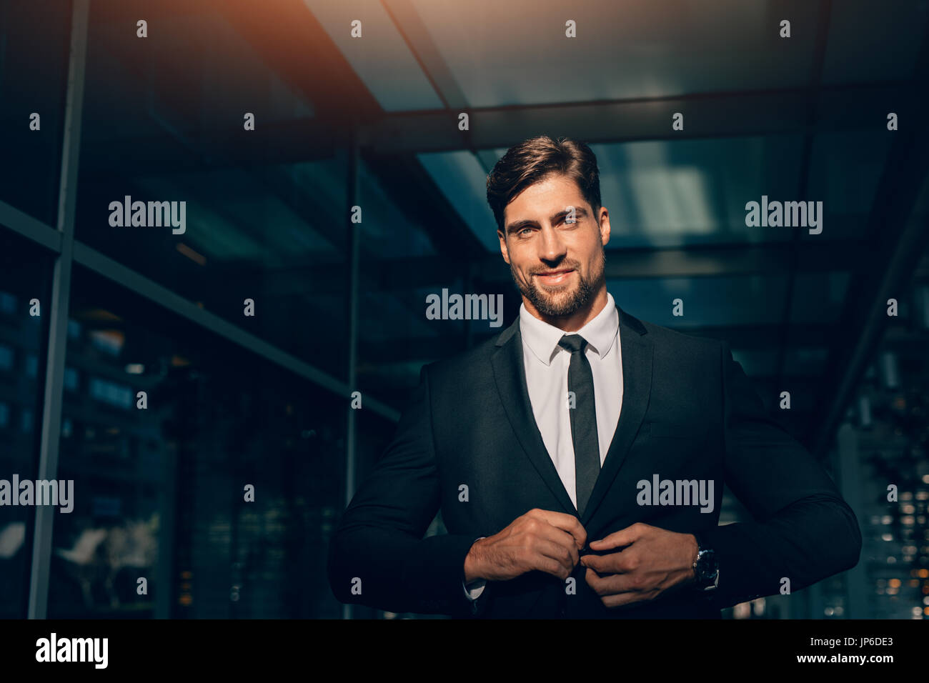Portrait of handsome young man in business suit looking at camera. He ...