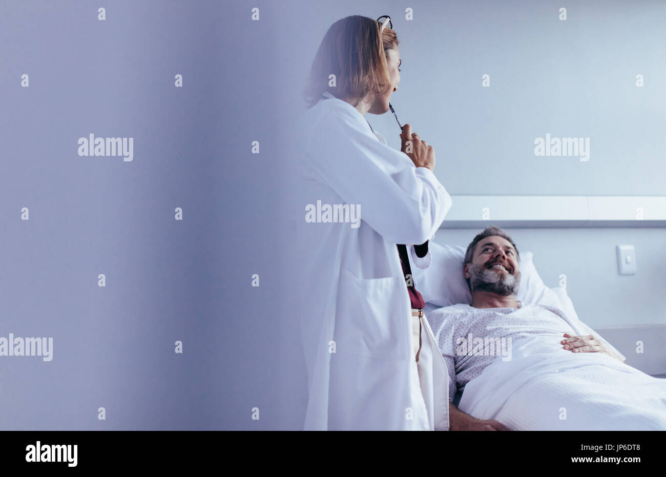 Female doctor talking to male patient lying in hospital bed. Medical ...