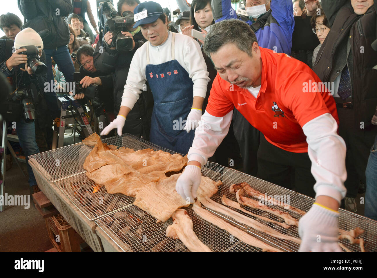 A dried giant squid is cut and grilled on a charcoal fire in Imizu