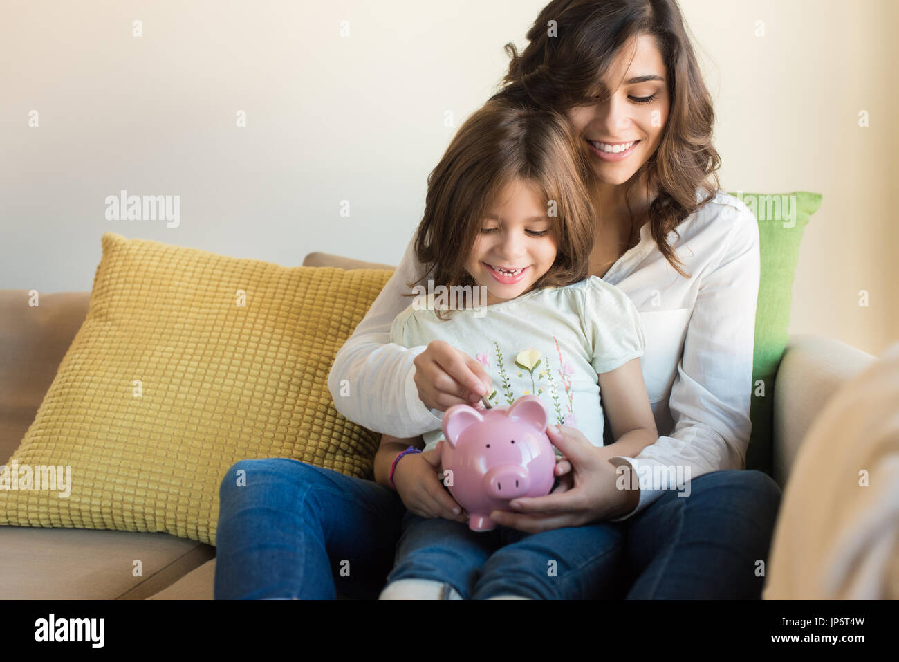 Mother and daughter putting coins into piggy bank Stock Photo - Alamy