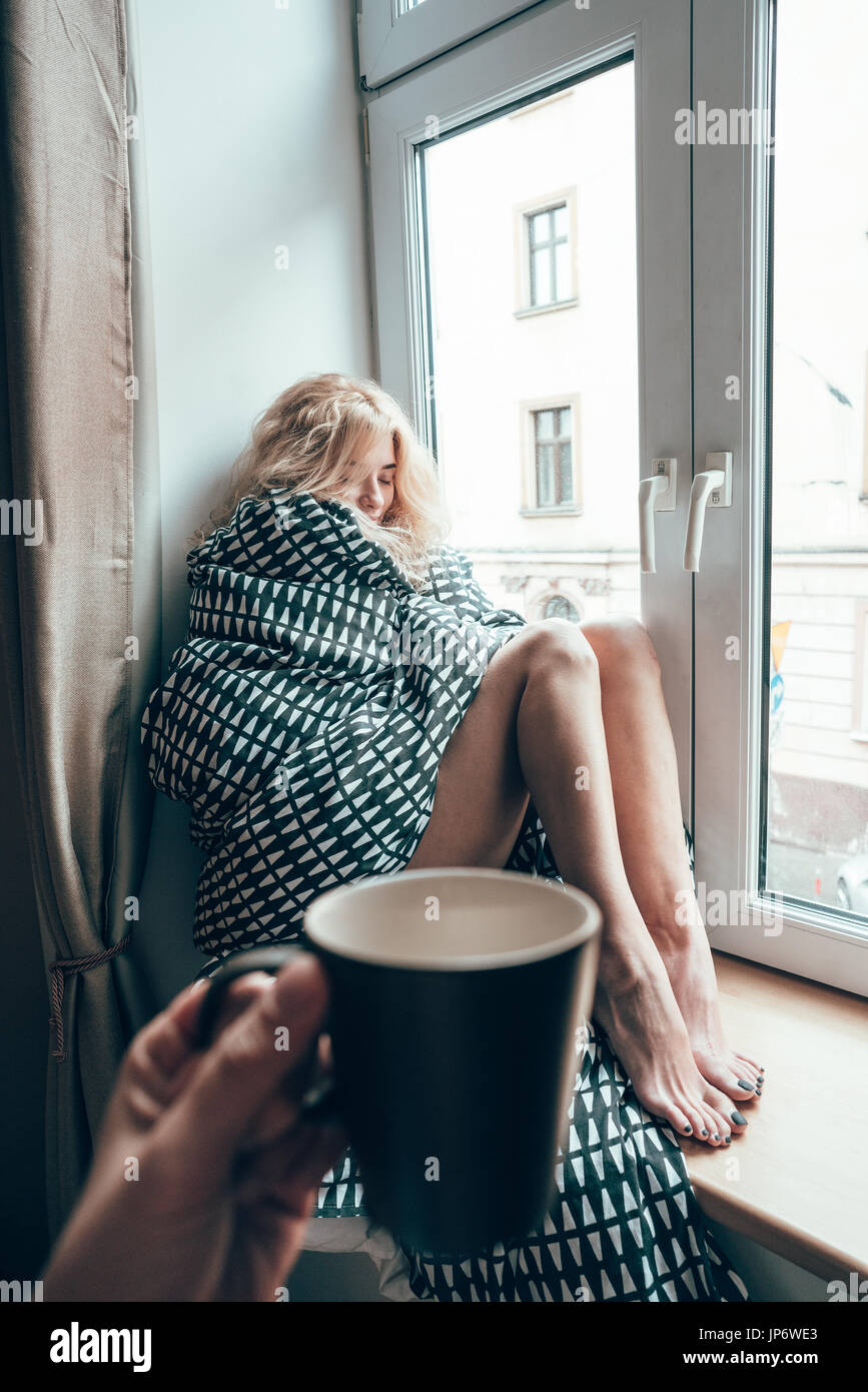 girl sitting on a window in a blanket Stock Photo Alamy