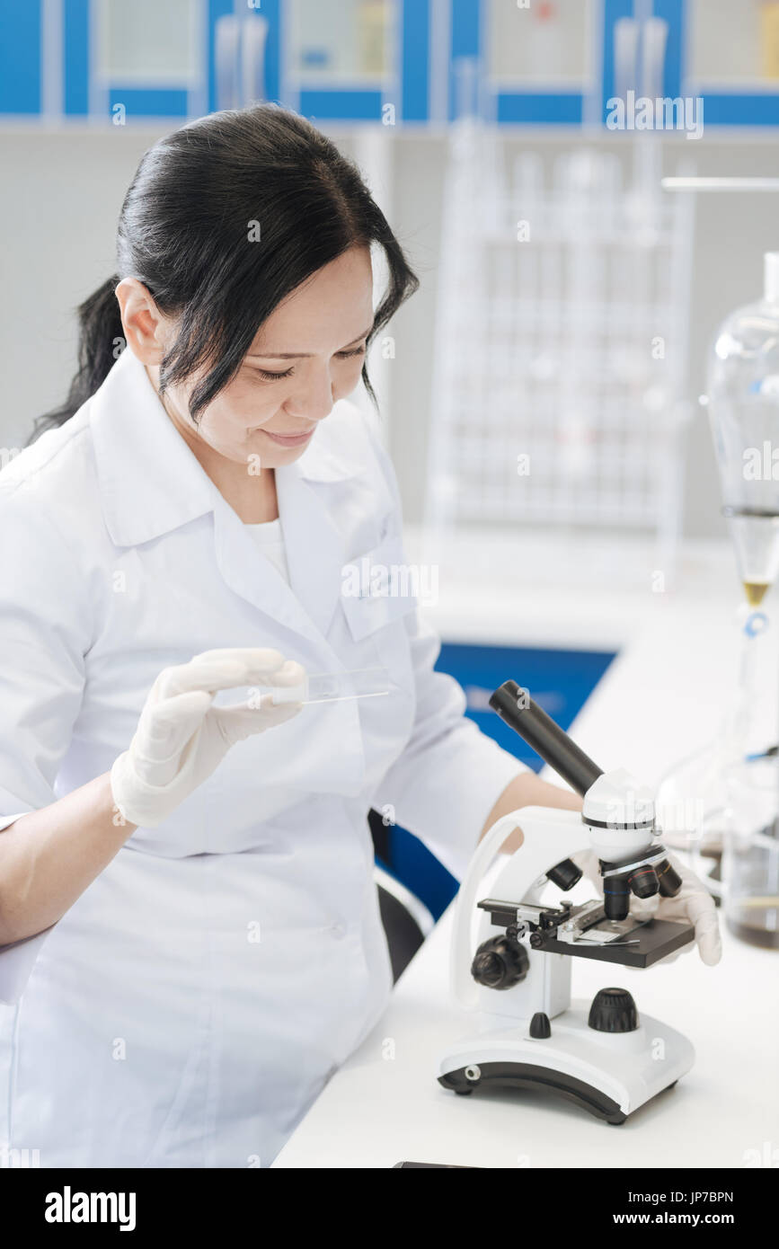 Pleasant professional biologist holding a microscope slide Stock Photo