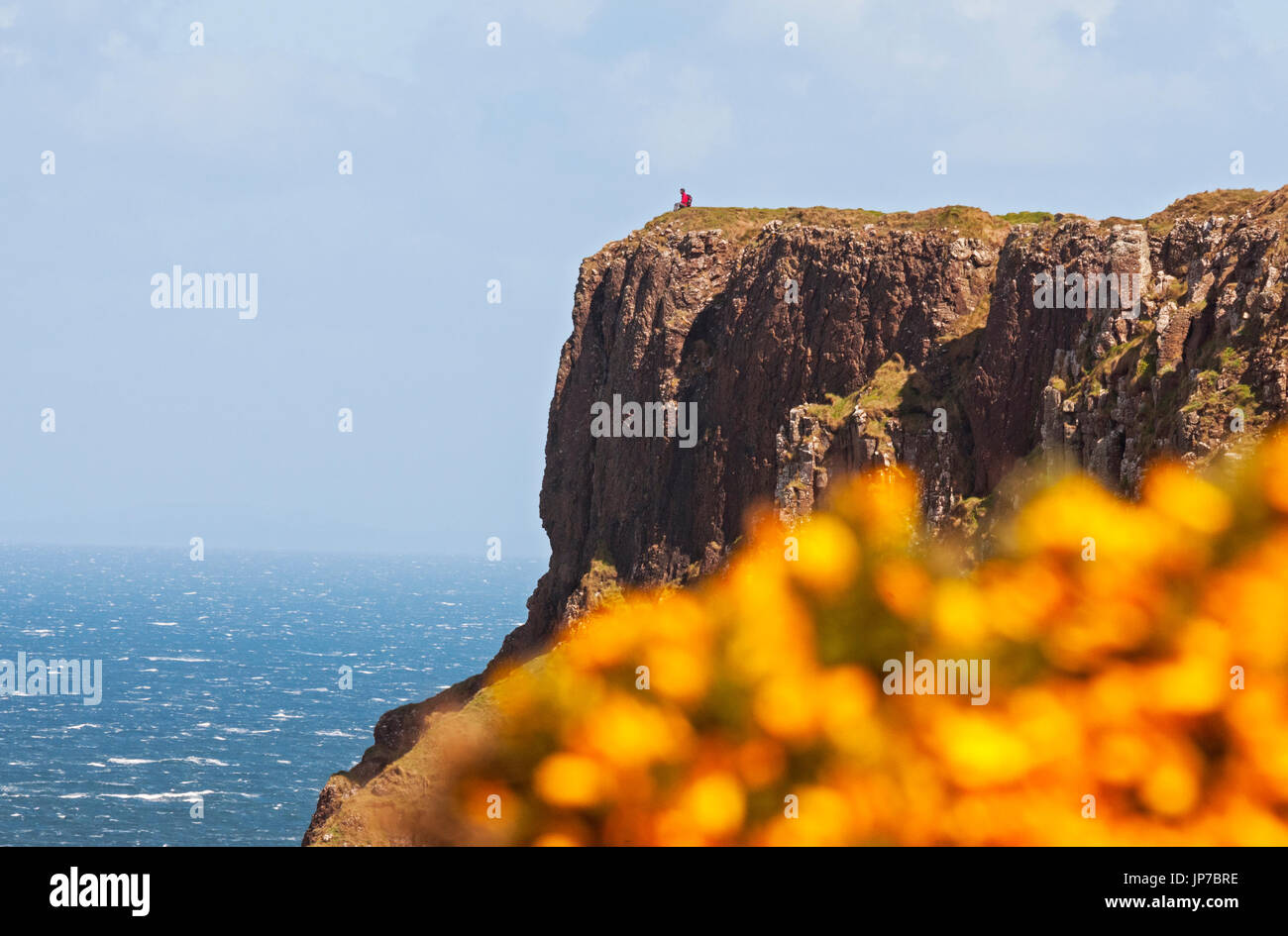 Person sitting on top of cliff near Giant's Causeway, Northern Ireland Stock Photo