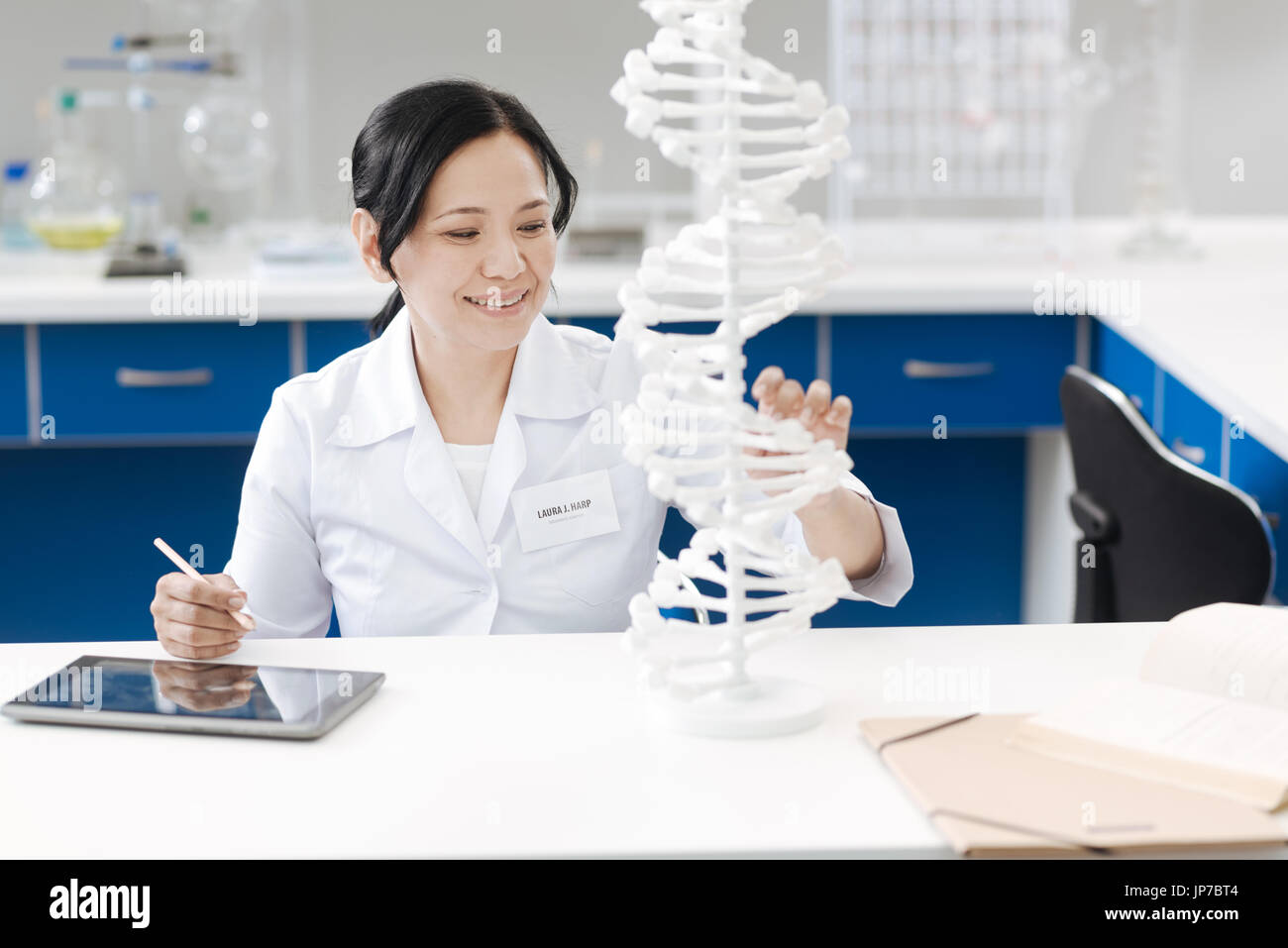Happy positive woman looking at the gene model Stock Photo