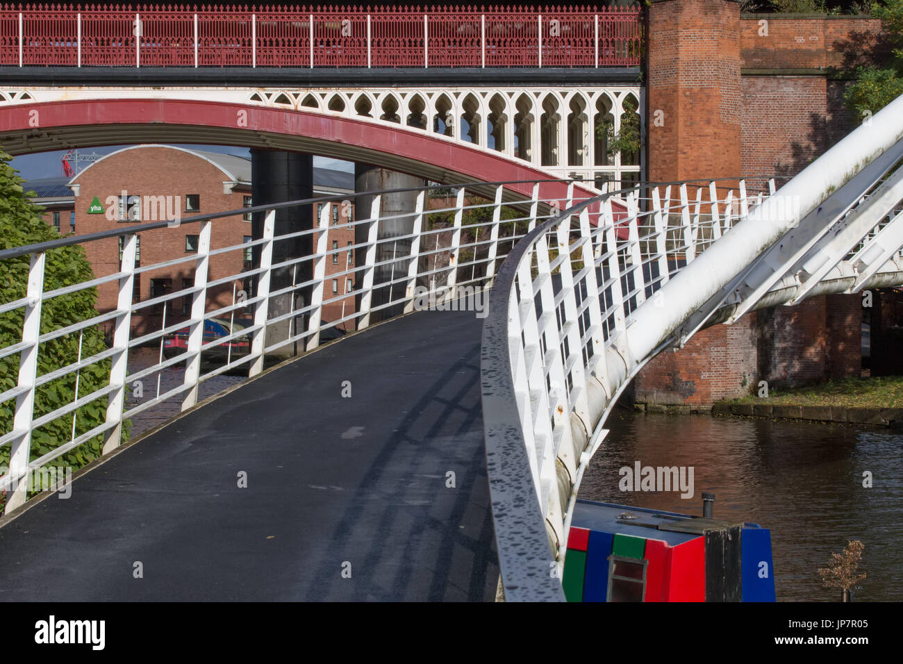 The modern Merchant’s Bridge in Castlefield Basin with the historical Victorian Rail Viaduct behind. Stock Photo