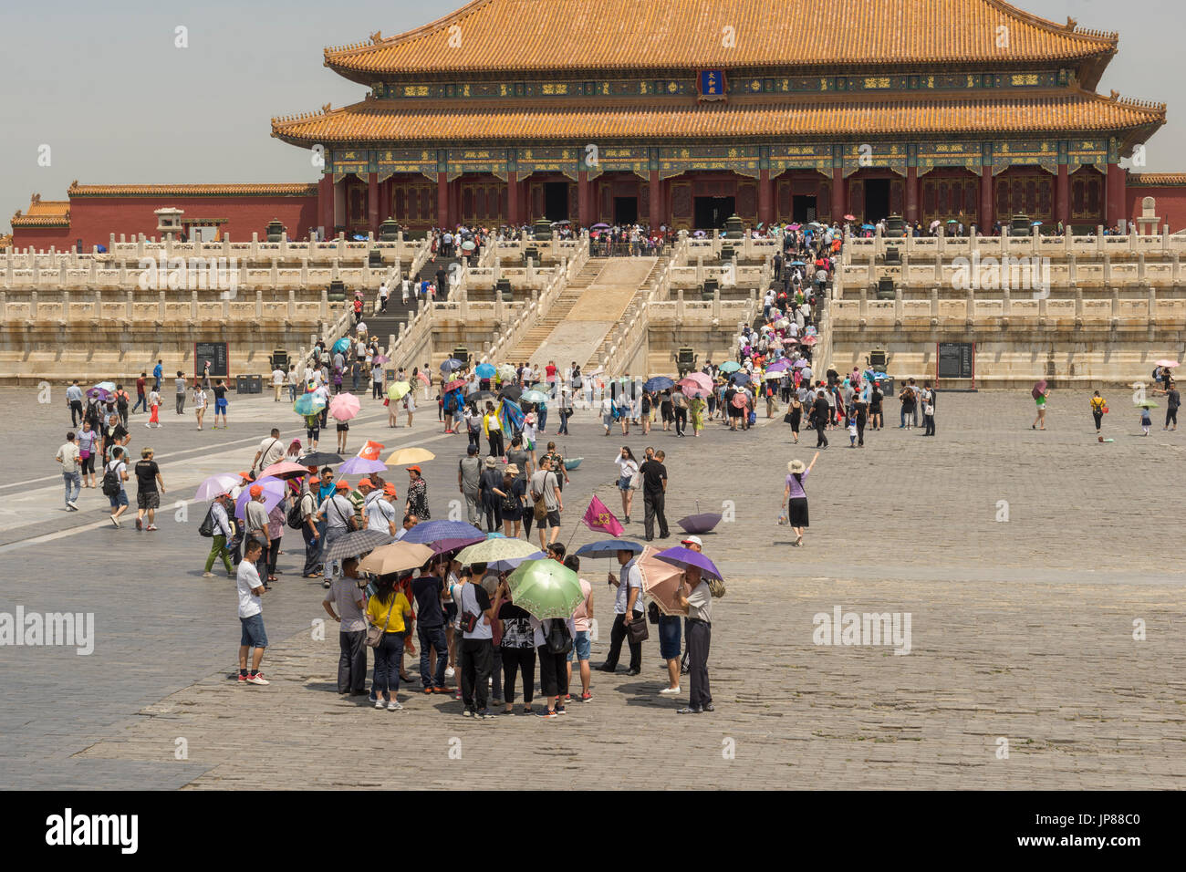 Tourists holding shade umbrellas approaching the Hall of Supreme Harmony in Forbidden City in Beijing China Stock Photo