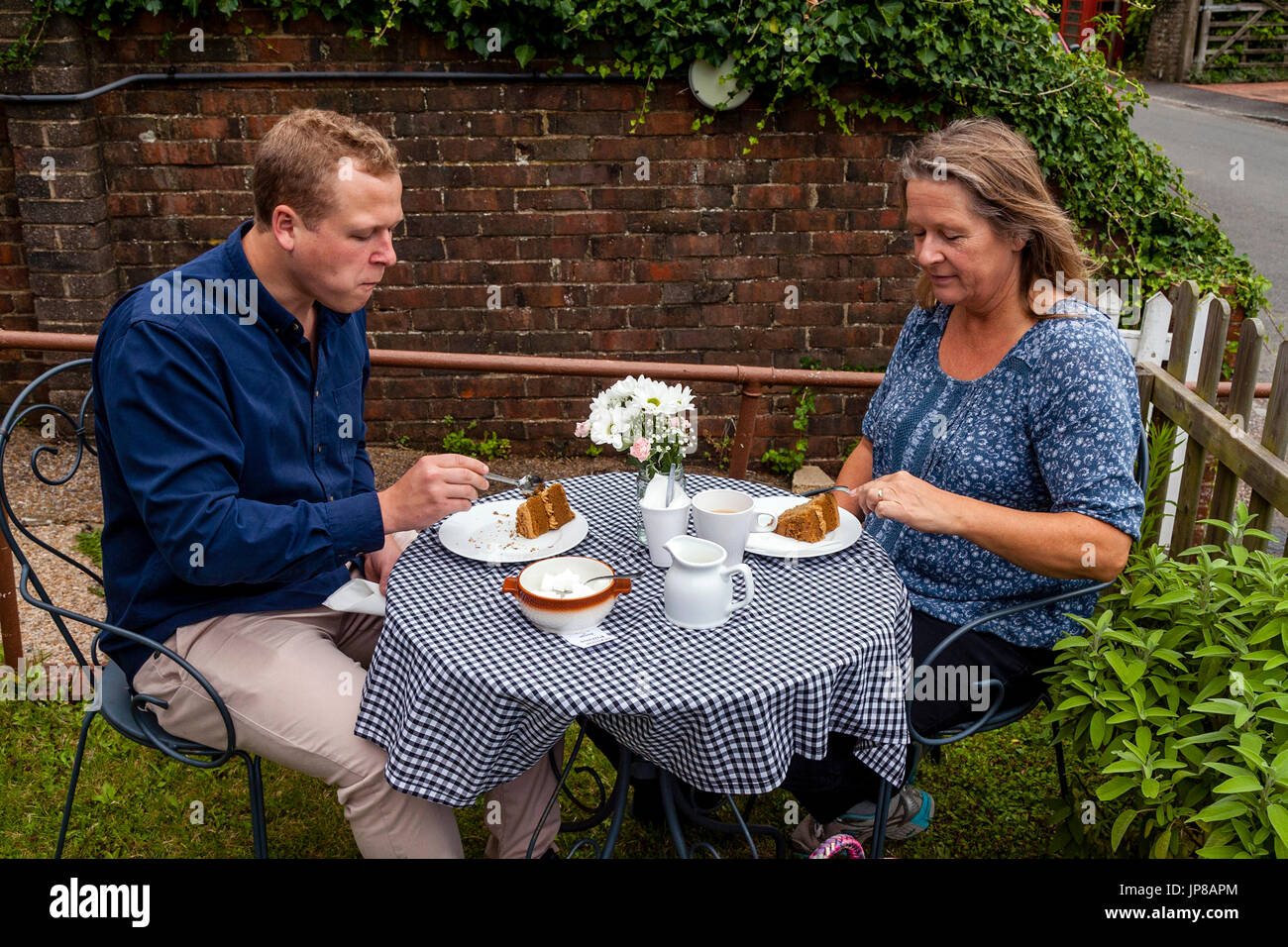 A mother and son enjoy tea and cakes in a cafe garden, Fulking, Sussex