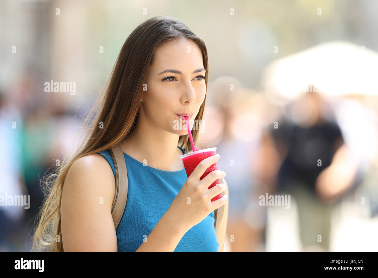 Single girl walking and sipping a slush in the street in summer Stock Photo