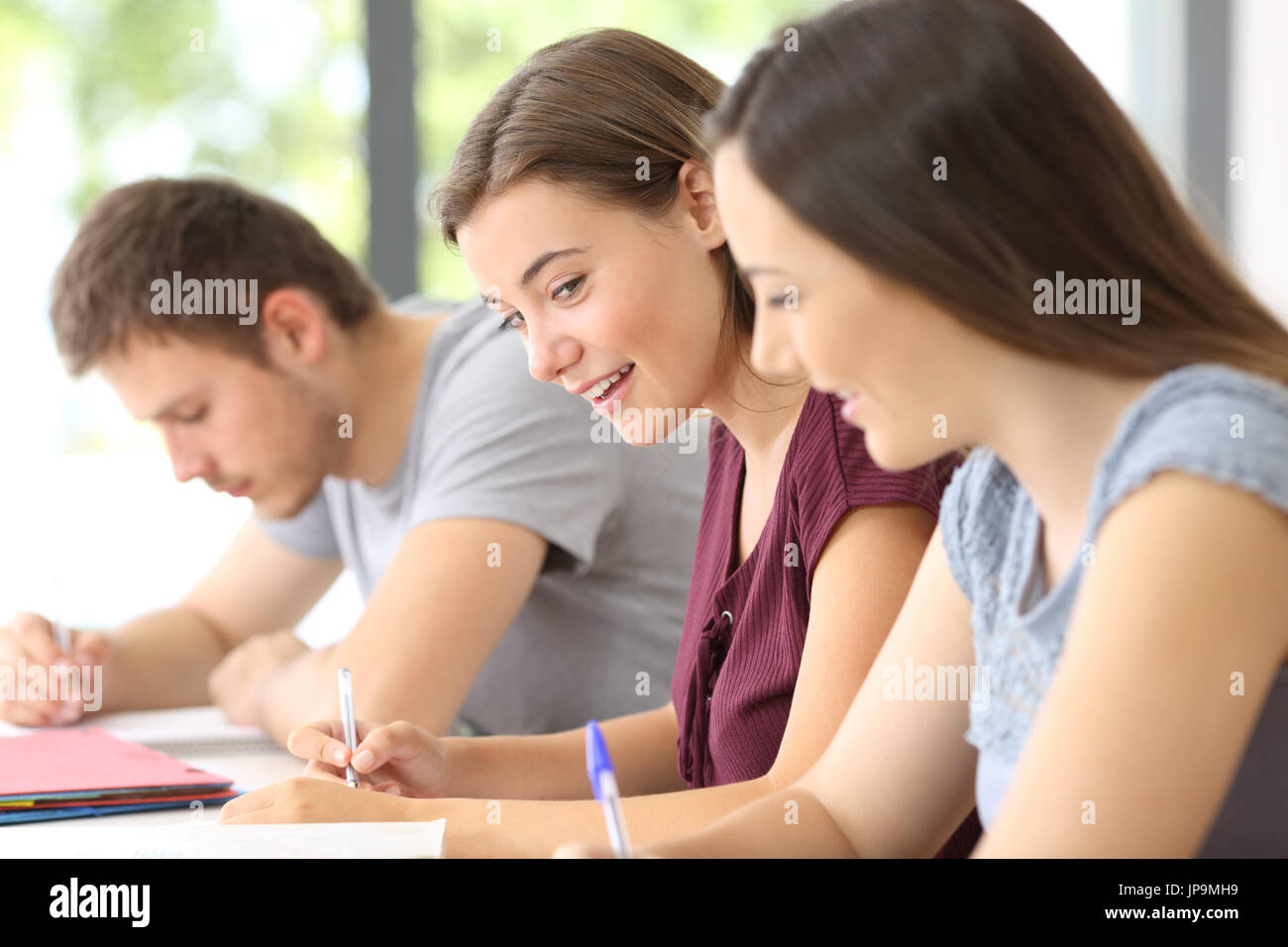 Two classmates talking during a class in a classroom Stock Photo