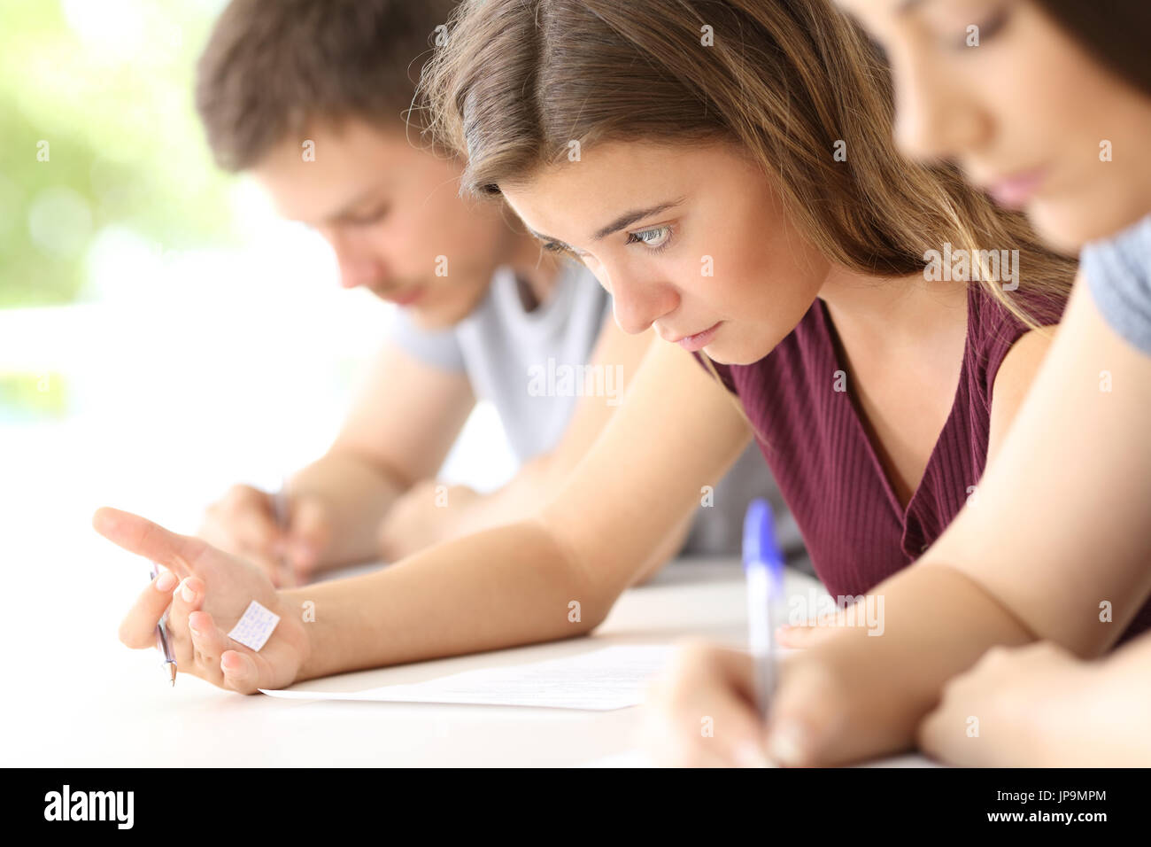 Bad student reading a cheating sheet during an exam in a classroom Stock Photo