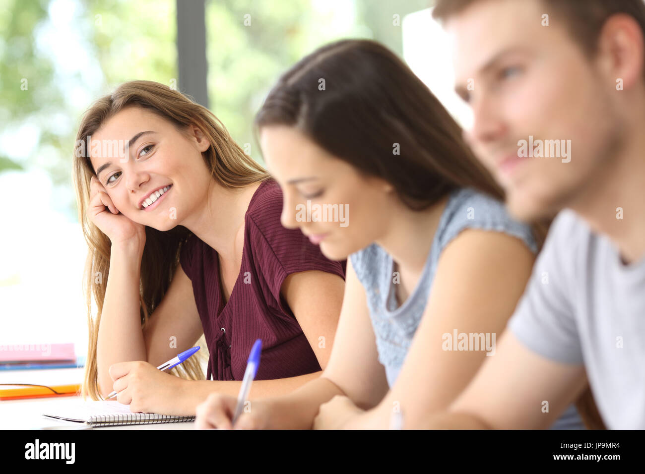 Student in love looking at a handsome classmate in a classroom Stock Photo