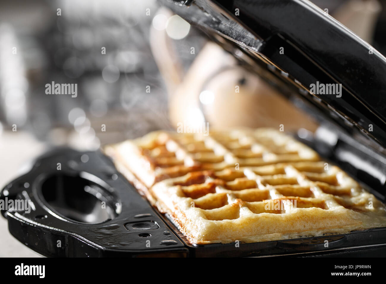 Freshly baked traditional Belgian waffles in iron waffle maker Stock Photo