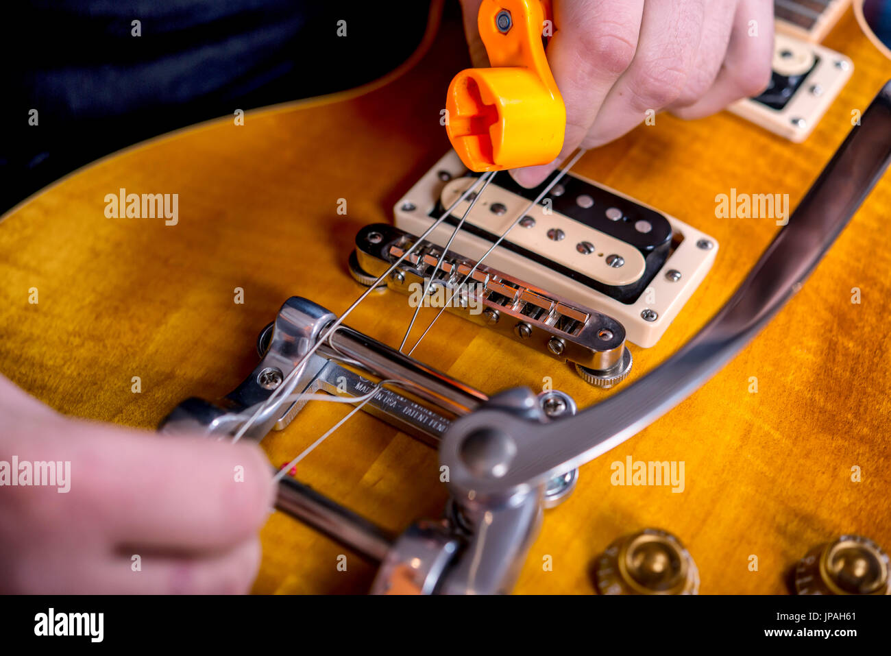 Musician in the sound studio changing the strings at the guitar, Stock Photo