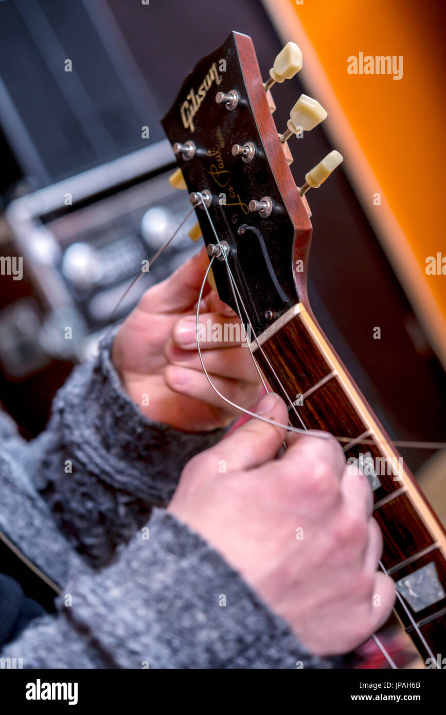 Musician in the sound studio changing the strings at the guitar, Stock Photo