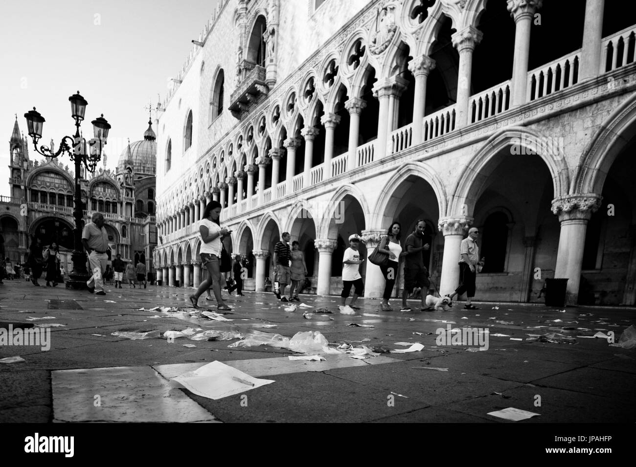 Garbage and person animate the early morning San Marco Platz in Venice, by a very low perspective and wide angle optics an unusual perspective comes about. Stock Photo