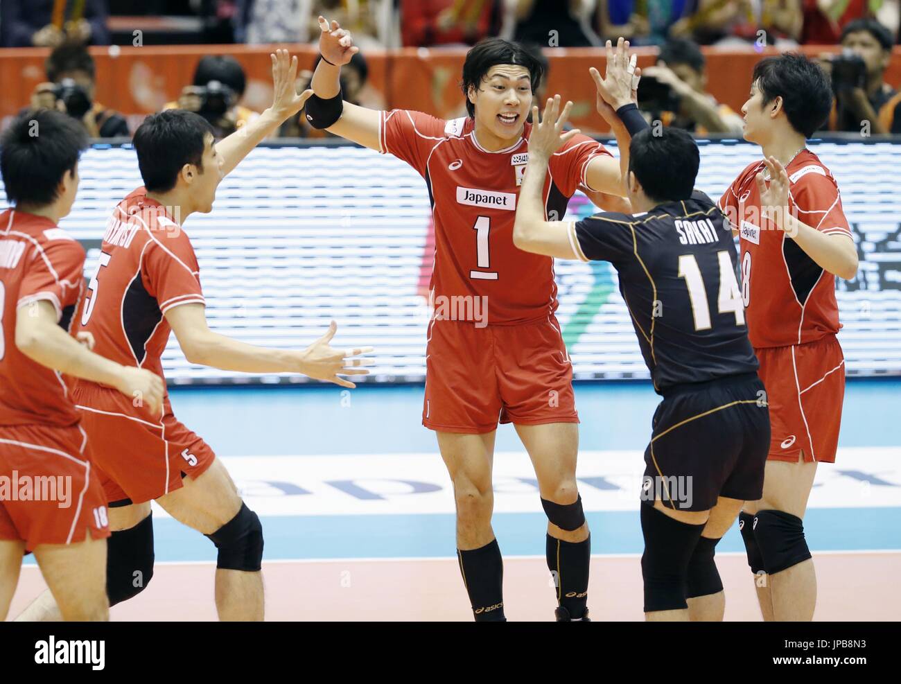 Members of the Japanese men's volleyball team celebrate after winning a point in the first set