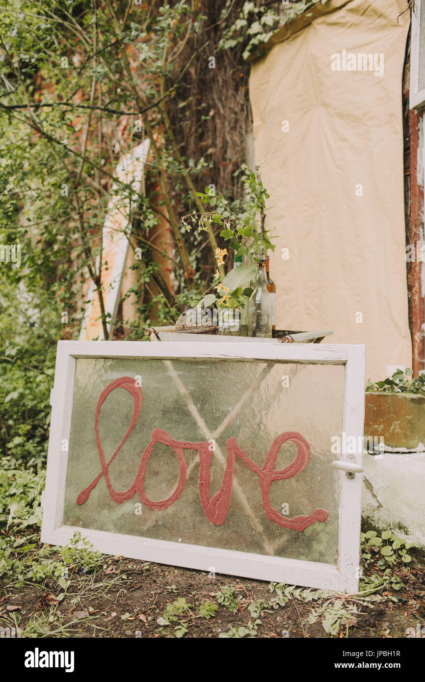 Garden, tree, sign / old window with the inscription 'Love' Stock Photo