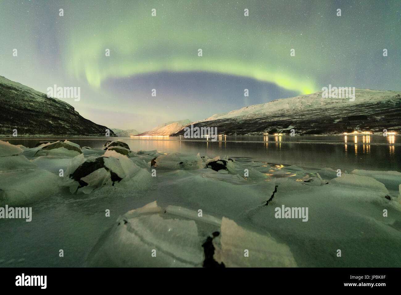 Northern Lights reflected in the cold sea frames the rocks covered with ice Manndalen Kafjord Lyngen Alps Tromsø Norway Europe Stock Photo