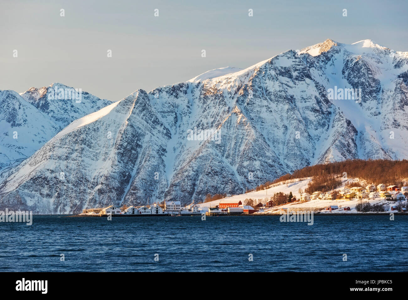 The typical fishing village of Hamnes framed by snowy peaks and the cold sea Lyngen Alps Tromsø Norway Europe Stock Photo