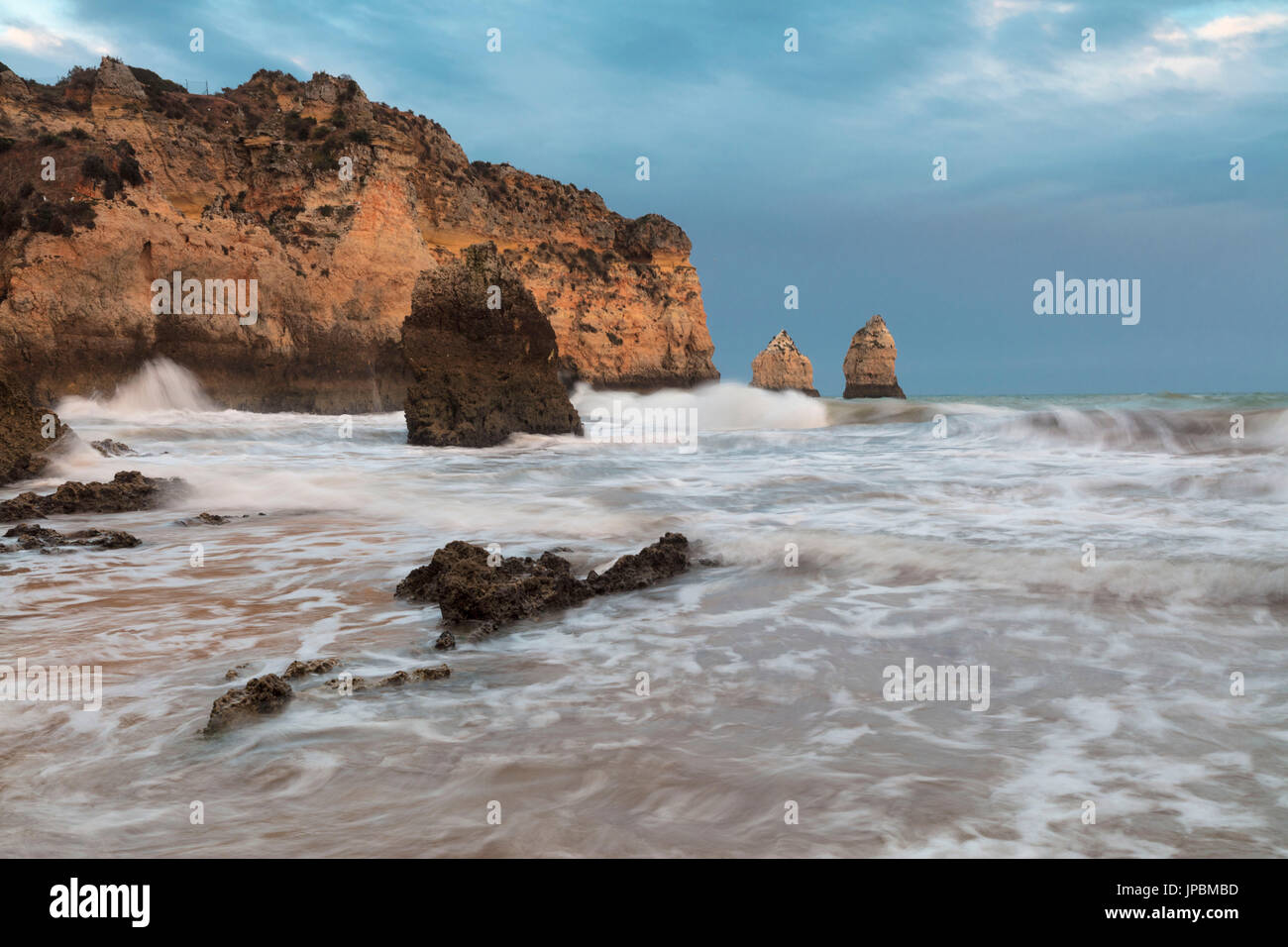 Clouds frame the rough sea and cliffs at sunset Praia Dos Tres Irmaos Portimao Algarve Portugal Europe Stock Photo