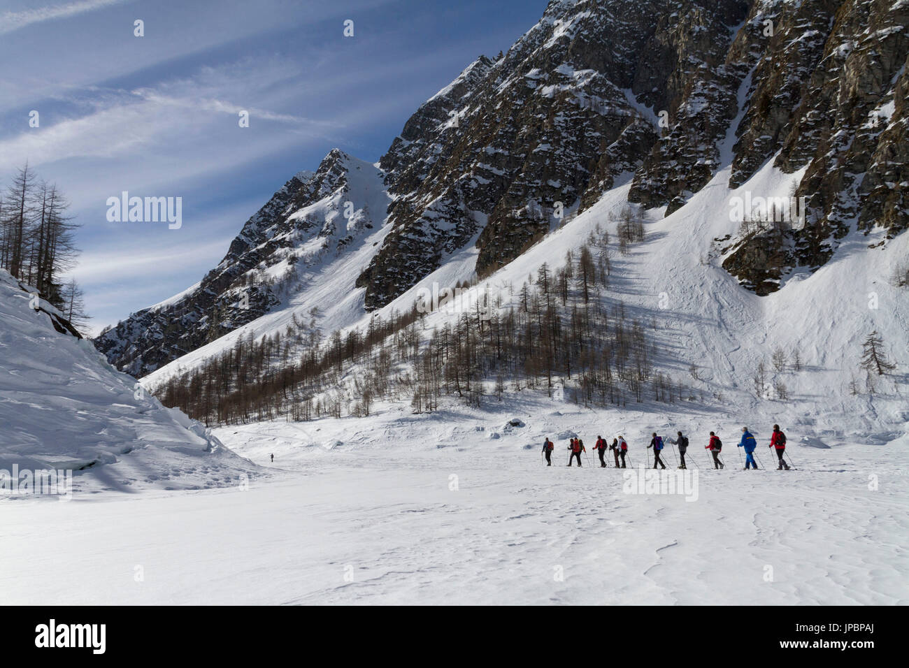 Snowshoeing on the frozen Devero Lake, in the Natural Park of Alpe Devero, Piedmont, Italy Stock Photo