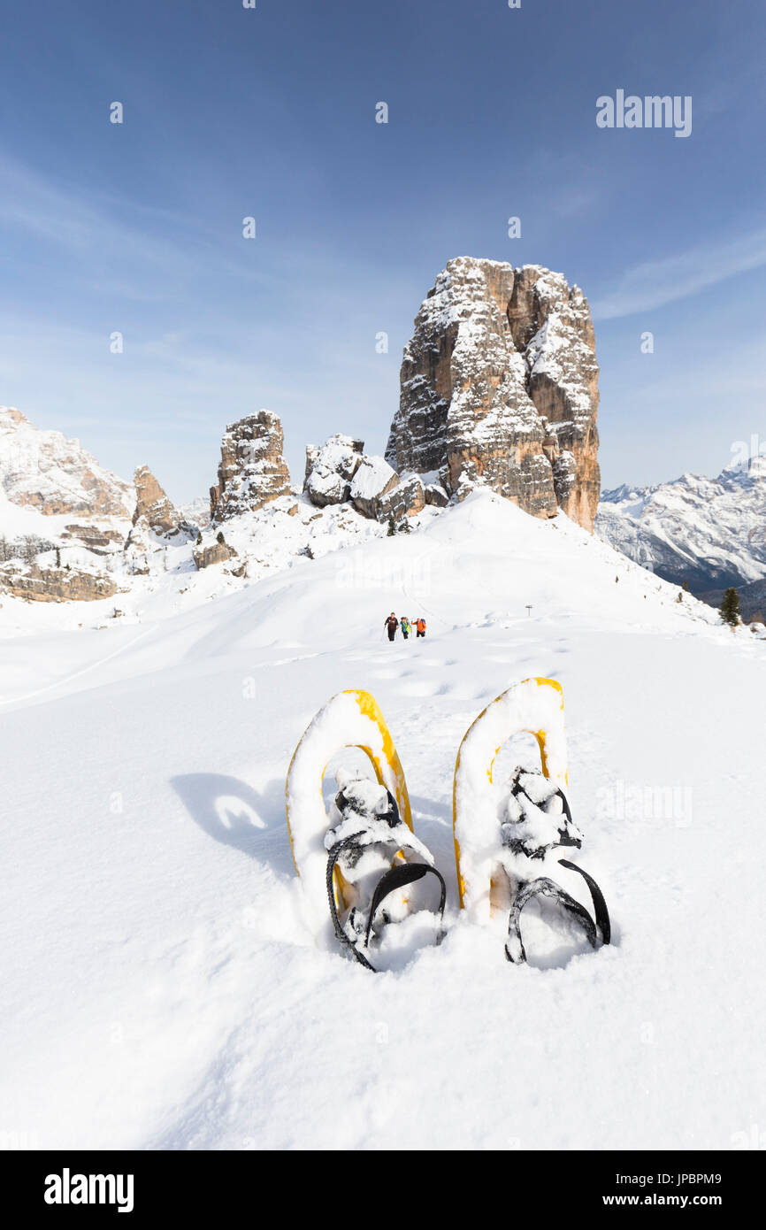 a view of the famous dolomitic group called Cinque Torri, with a group of hikers in the background and a pair of snowshoes in the foreground, Belluno province, Veneto, Italy, Europe Stock Photo