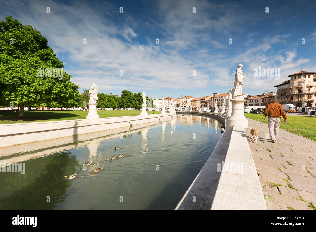 a detail of Prato della Valle, with his typical circular canal and a man with his dog walking around it, padua province, veneto, italy, europe, Stock Photo